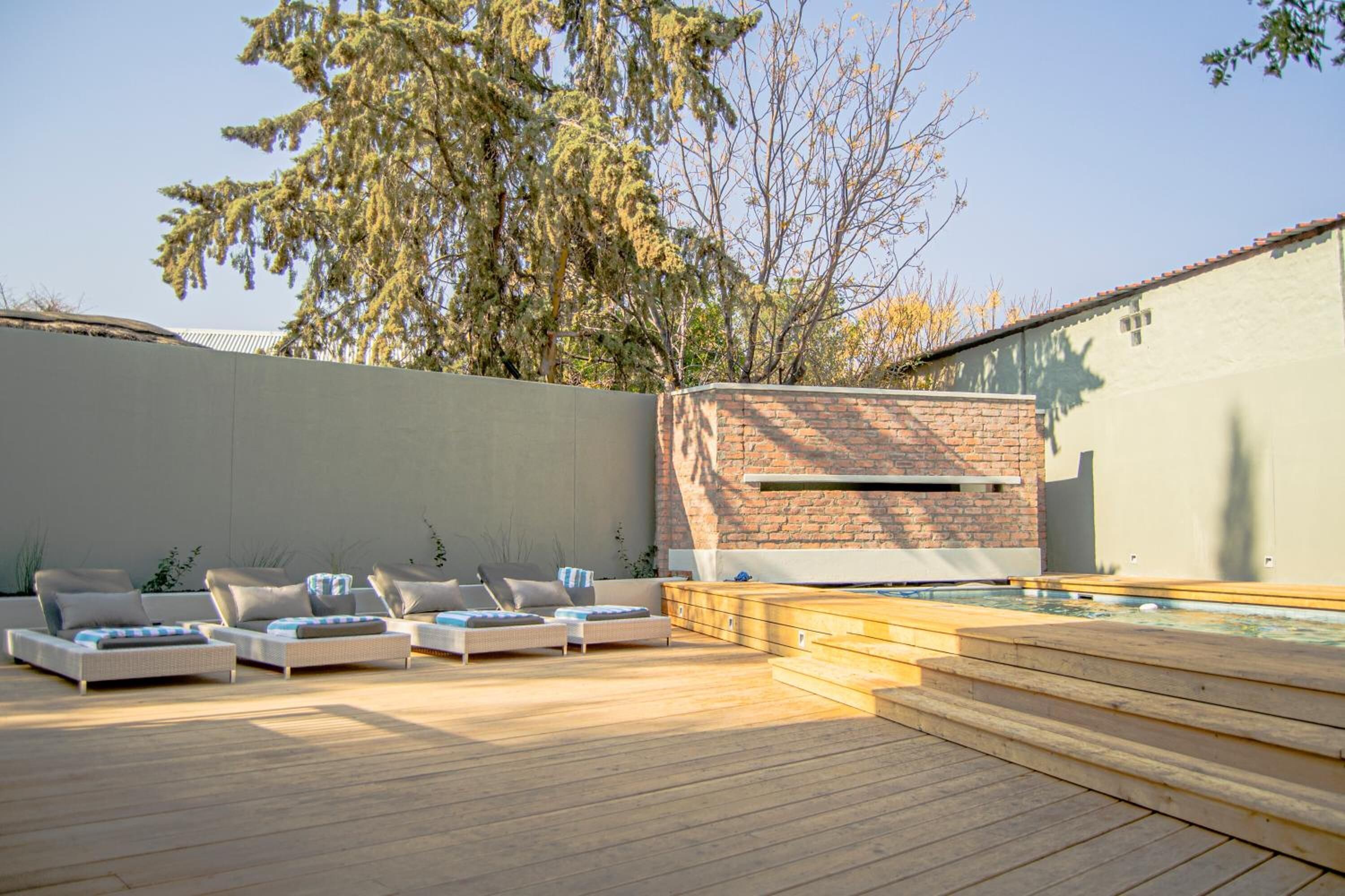Una terraza de madera con sillones de descanso y una pequeña piscina.