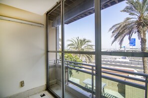 A balcony with a view of palm trees and a road.