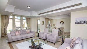Ein geräumiges Wohnzimmer mit einem großen Sofa, Sesseln und einem Glastisch.