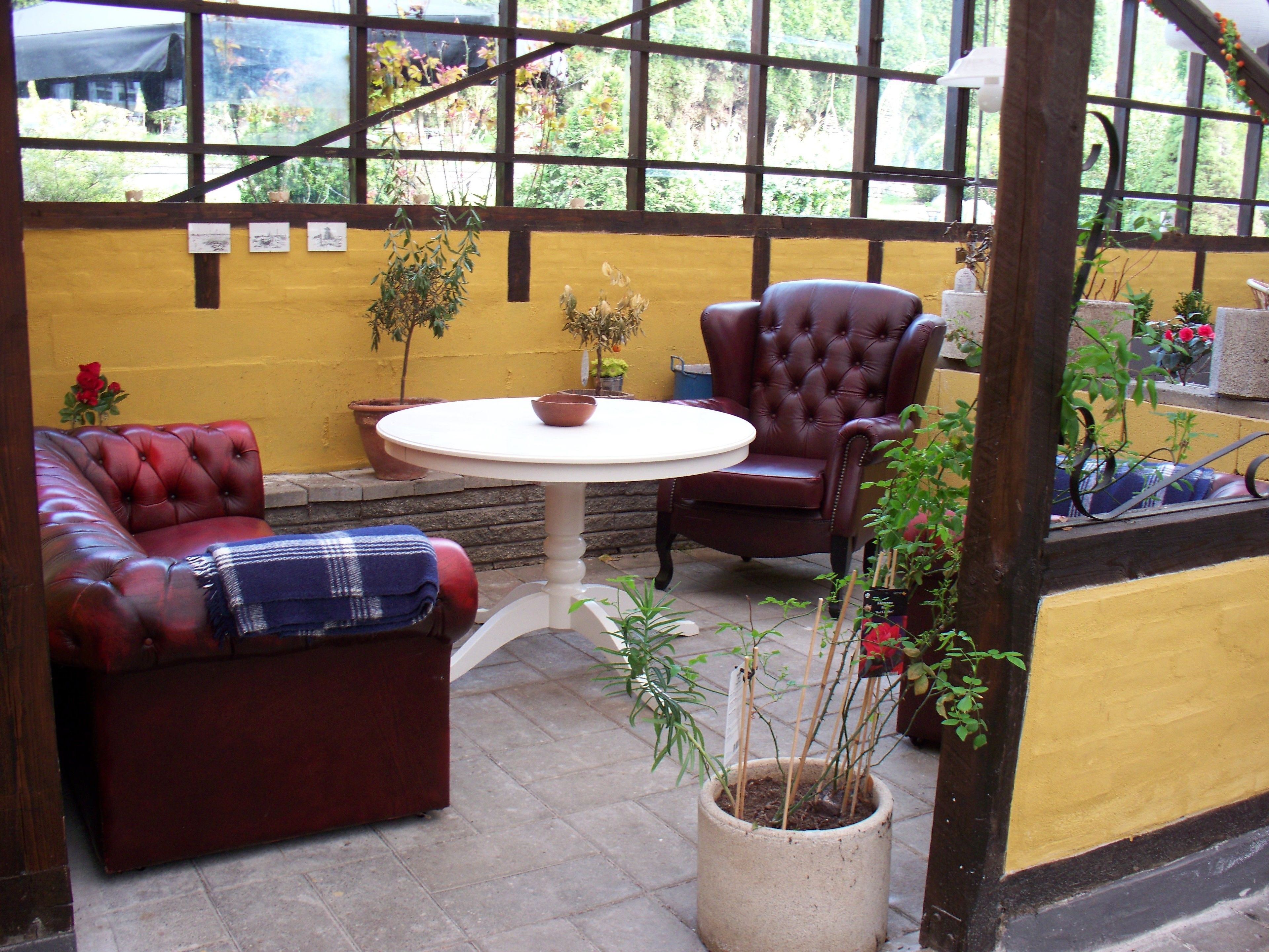 A cozy patio area with a round table, two leather sofas, and a potted plant.