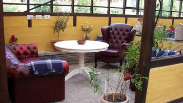 Een gezellig terras met een ronde tafel, twee leren banken en een potplant.