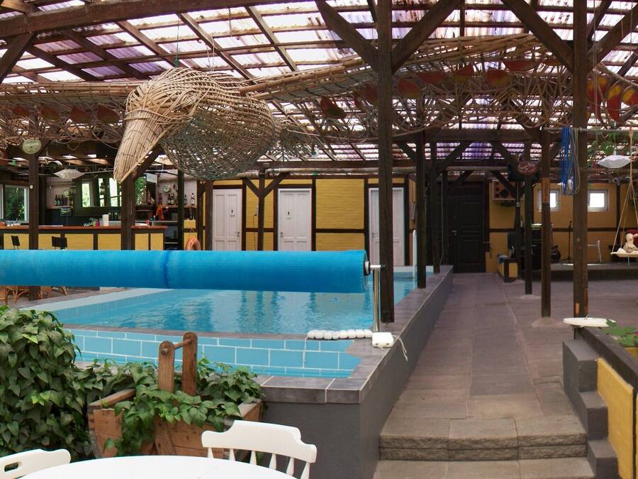 Un área de piscina interior con techo cubierto, asientos y un bar.