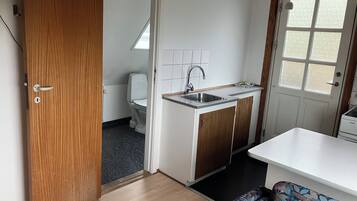 Pieni, käytännöllinen keittiönurkkaus, jossa on pesuallas, wc ja pieni ikkuna.