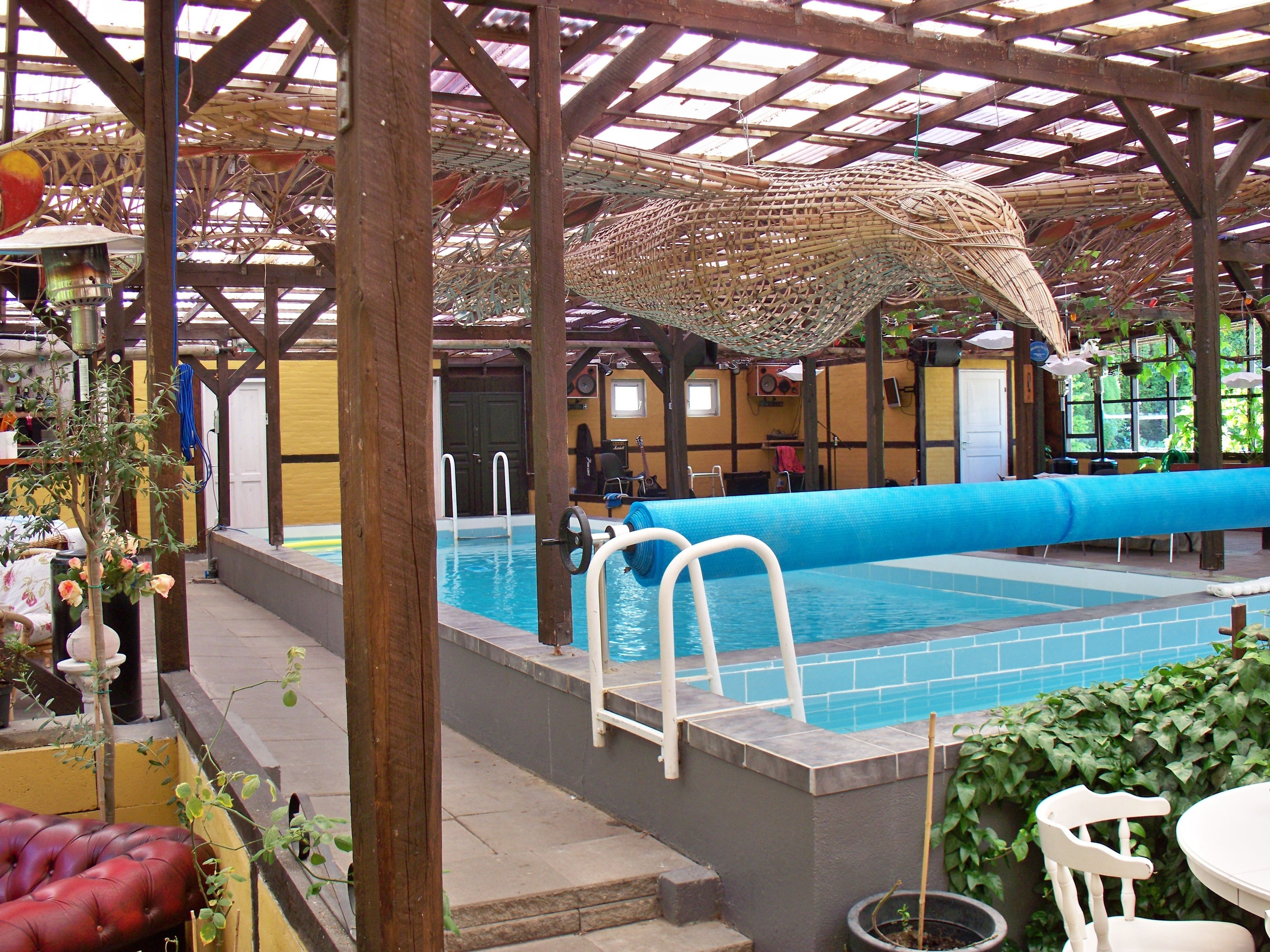 An outdoor pool area with a covered roof, a diving board, and a lounge chair.