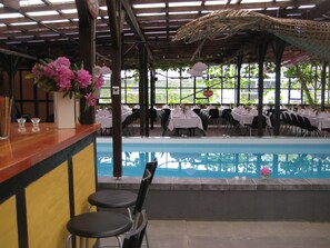 A restaurant with a pool, tables set for dining, and chairs. - Danninghus (Svendborg)