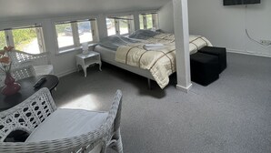 A bedroom with a skylight, a bed, a TV, and a seating area with a table and chairs.