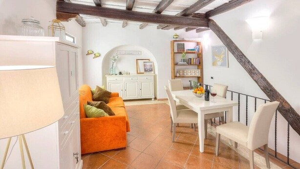 Una sala de estar acogedora con un sofá, una mesa de comedor y una escalera.