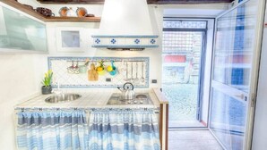 Una cocina con cortina a rayas, salpicadero de azulejos y ventana con vista a un patio.