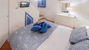 Un dormitorio con una cama, un aparador, un televisor y una escalera.