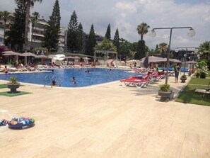Una piscina al aire libre de temporada, sombrillas