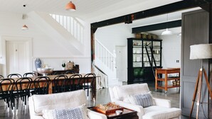 Un vaste espace de vie comprenant un escalier, un ensemble de salle à manger et un jeu d’échecs posé sur une table basse.