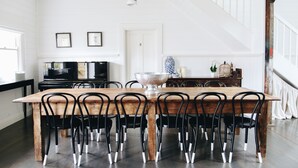 Un coin repas avec une table en bois et des chaises noires, une porte blanche et un escalier.