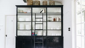 Un buffet noir aux portes vitrées, contenant de la vaisselle et des verres blancs.