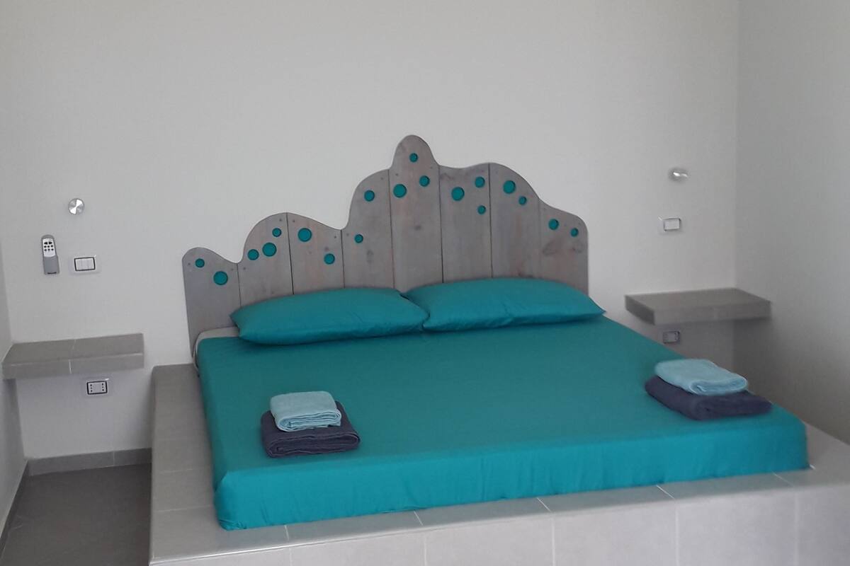 A bedroom with a bed, a ceiling fan, and a nightstand.