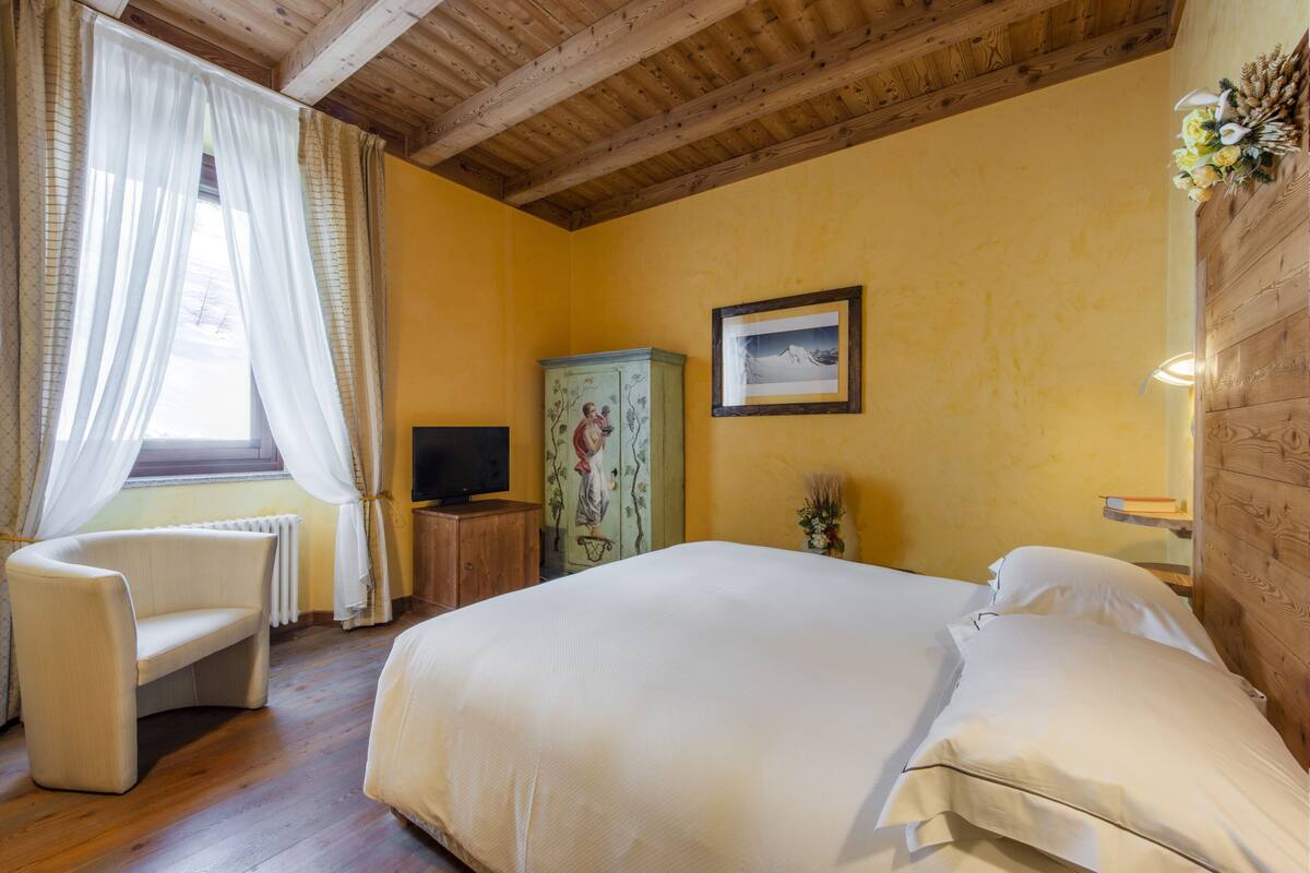 A bedroom with a bed, a chair, a television, and a cabinet.