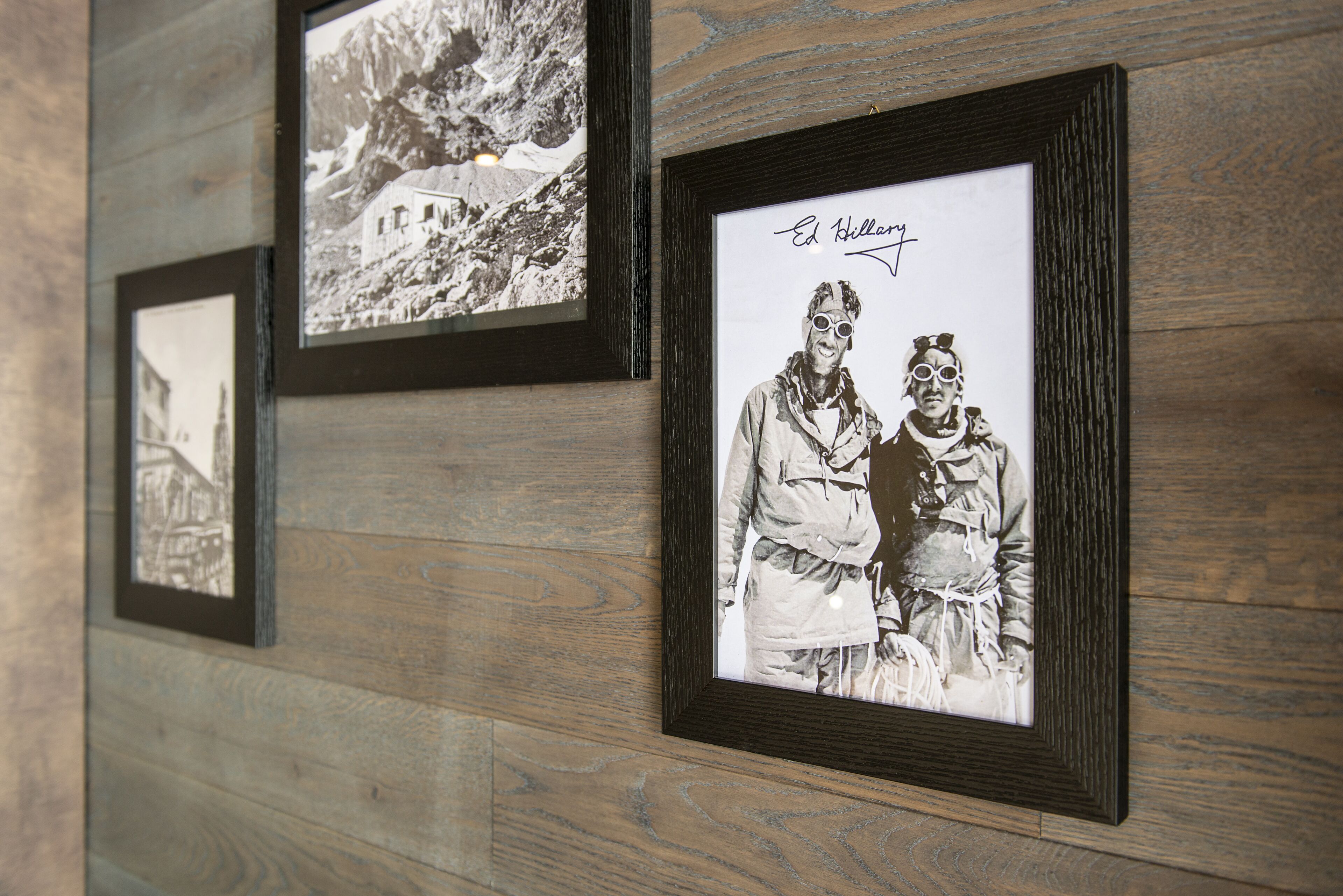 A wall with framed photographs, including a mountain scene and a person with goggles.