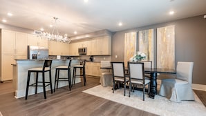 Een moderne keuken met een centraal eiland, barstoelen en een eethoek met een donker houten tafel en stoelen.