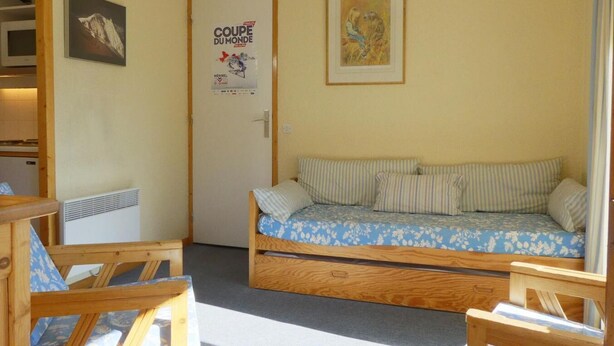Een gezellige kamer met een bed, een houten bankje en een poster aan de muur.