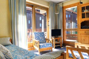 A room with a bed, a chair, a television, and a cabinet.