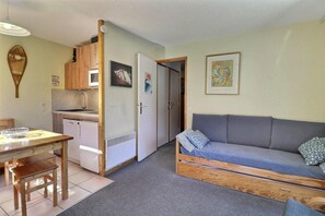 A compact living space with a kitchenette, a sofa, and a dining table.
