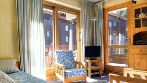 Een gezellige kamer met een bed, een stoel, een televisie en een kast.