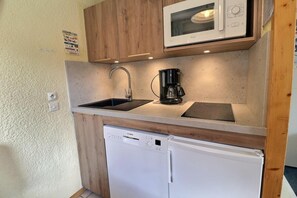A compact kitchen with a microwave, coffee maker, sink, and dishwasher.
