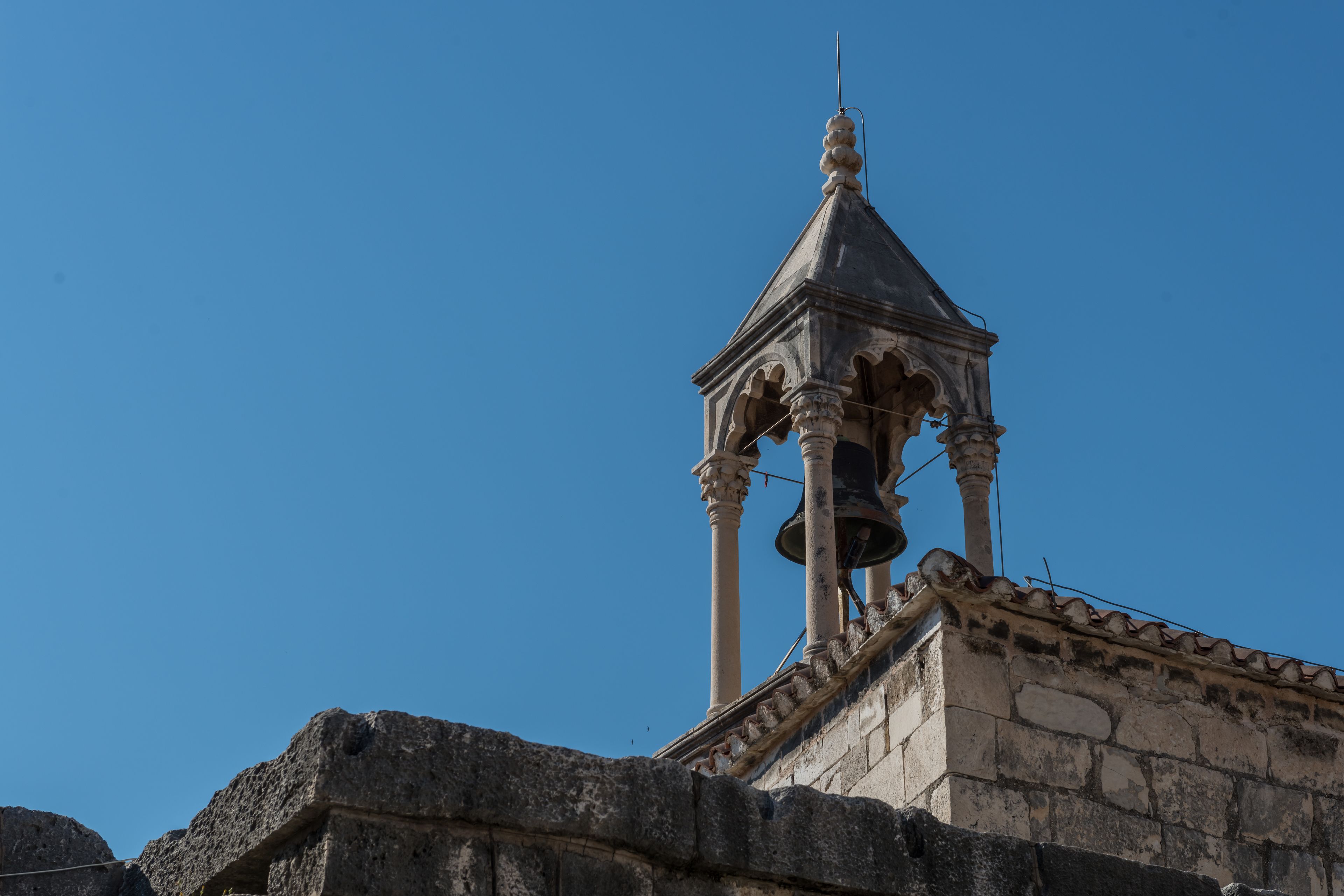 A bell tower with a clear blue sky in the background.