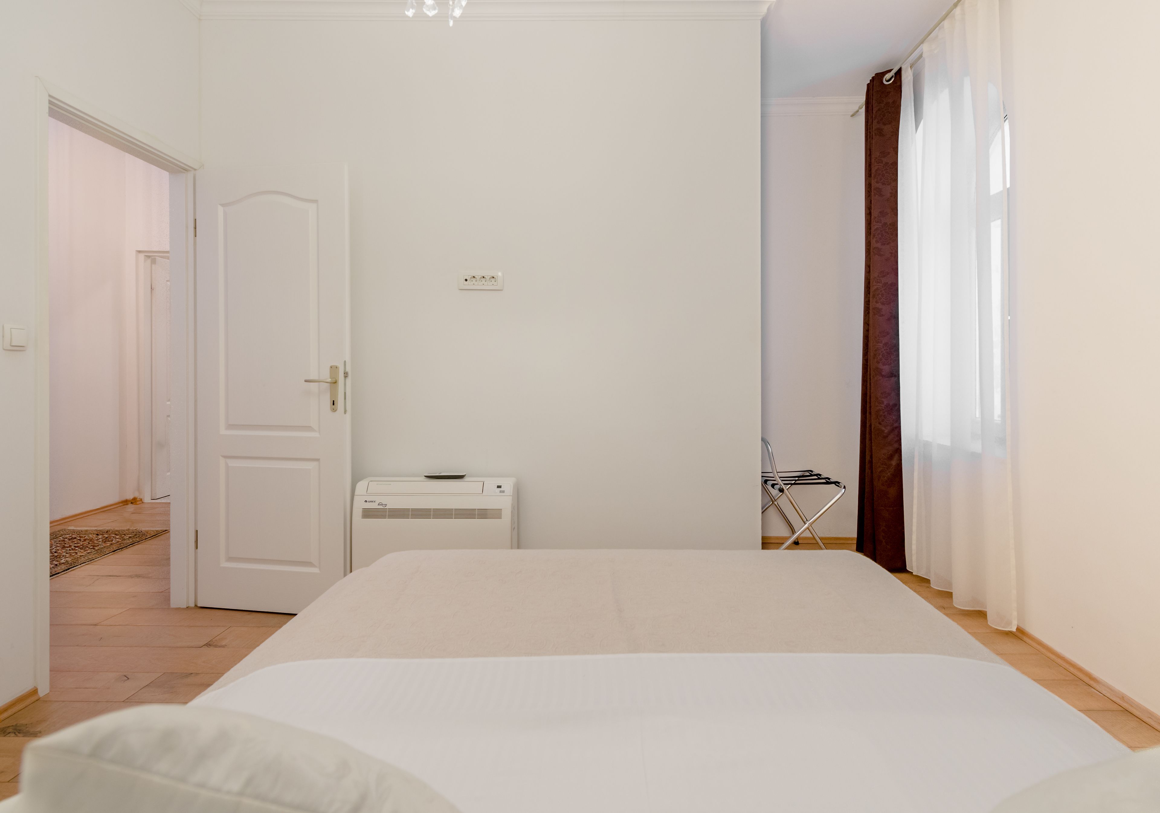 Camera da letto con un letto grande, un condizionatore d'aria bianco, una porta e una finestra con tende.