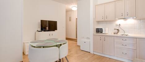 A modern kitchen with white cabinets, a microwave, and a glass-top dining table with chairs.