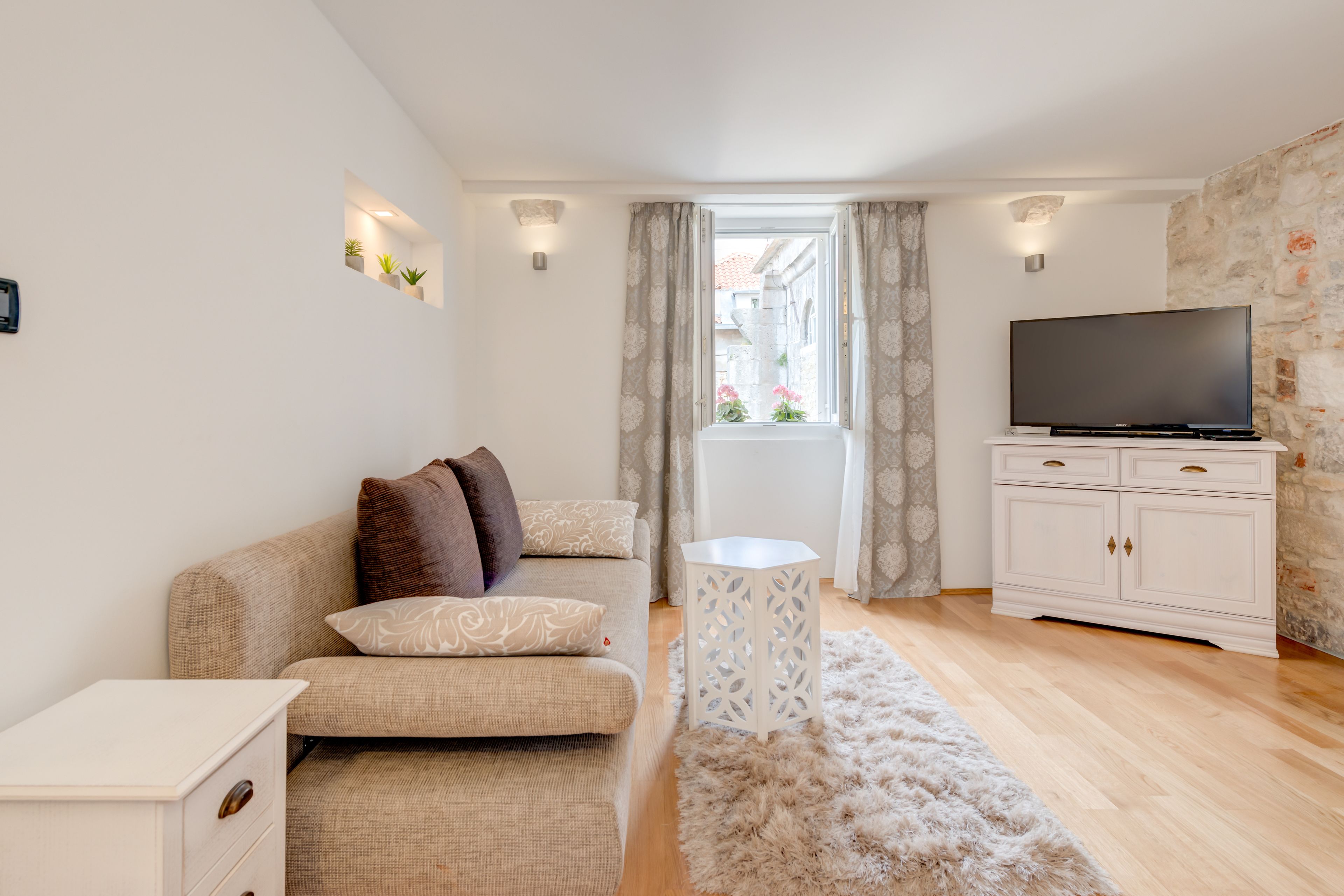 A modern living room with a sofa, a flat-screen TV, a small side table, and a white cabinet.