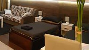 Een hotelkamer met een groot bed, een bank, een nachtkastje en een decoratief wandpaneel.