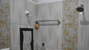 Een badkamer met een wastafel, spiegel, douche en decoratieve tegels.