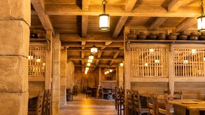A long, narrow hallway with wooden walls and ceiling, lined with tables and chairs. - Les Quais de Lutèce (Plailly)