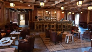 A rustic interior with wooden beams, a bar area, and seating arrangements. - Les Quais de Lutèce (Plailly)