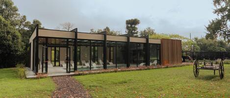 A modern building with large glass windows, a gravel path leading to it, and a carriage in the foreground.