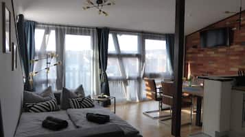Ein modernes Schlafzimmer mit Bett, Schreibtisch und Blick auf die Stadt.