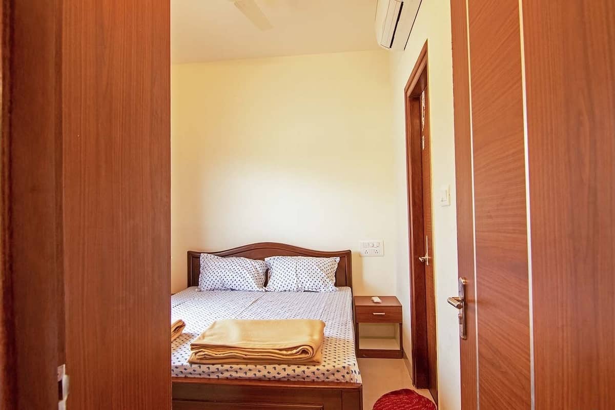 A bedroom with a bed, bedside table, and a wooden wardrobe.