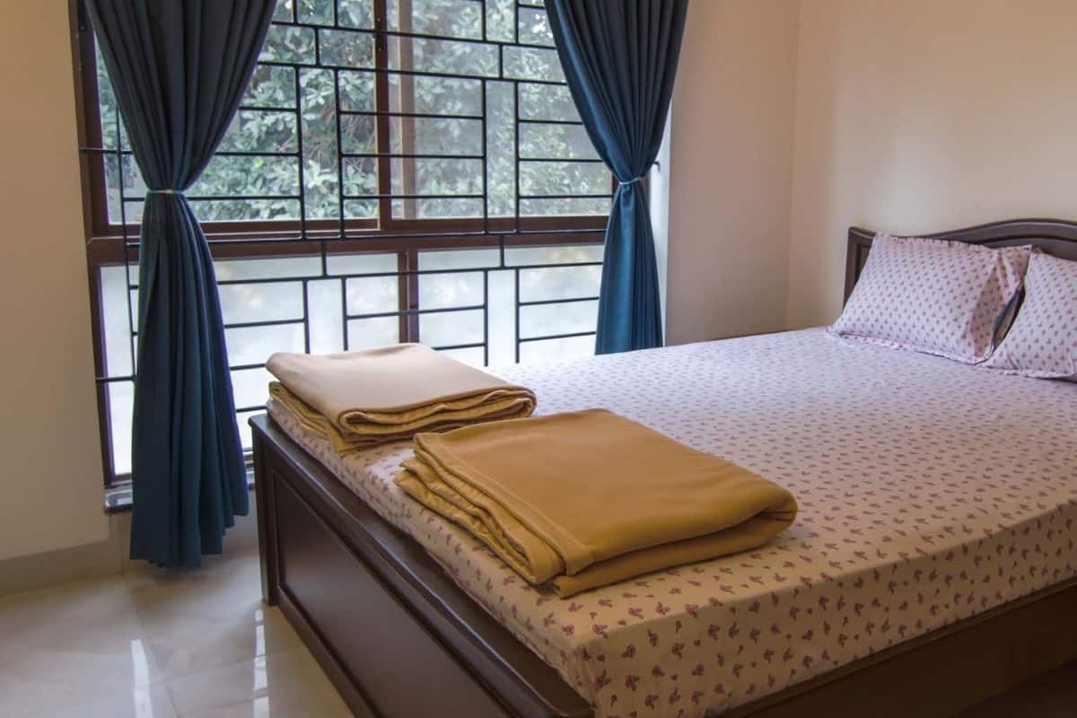 A neatly made bed with a patterned bedspread, pillows, and folded blankets.