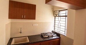 A kitchen with wooden cabinets, a sink, a gas stove, and a window with bars.