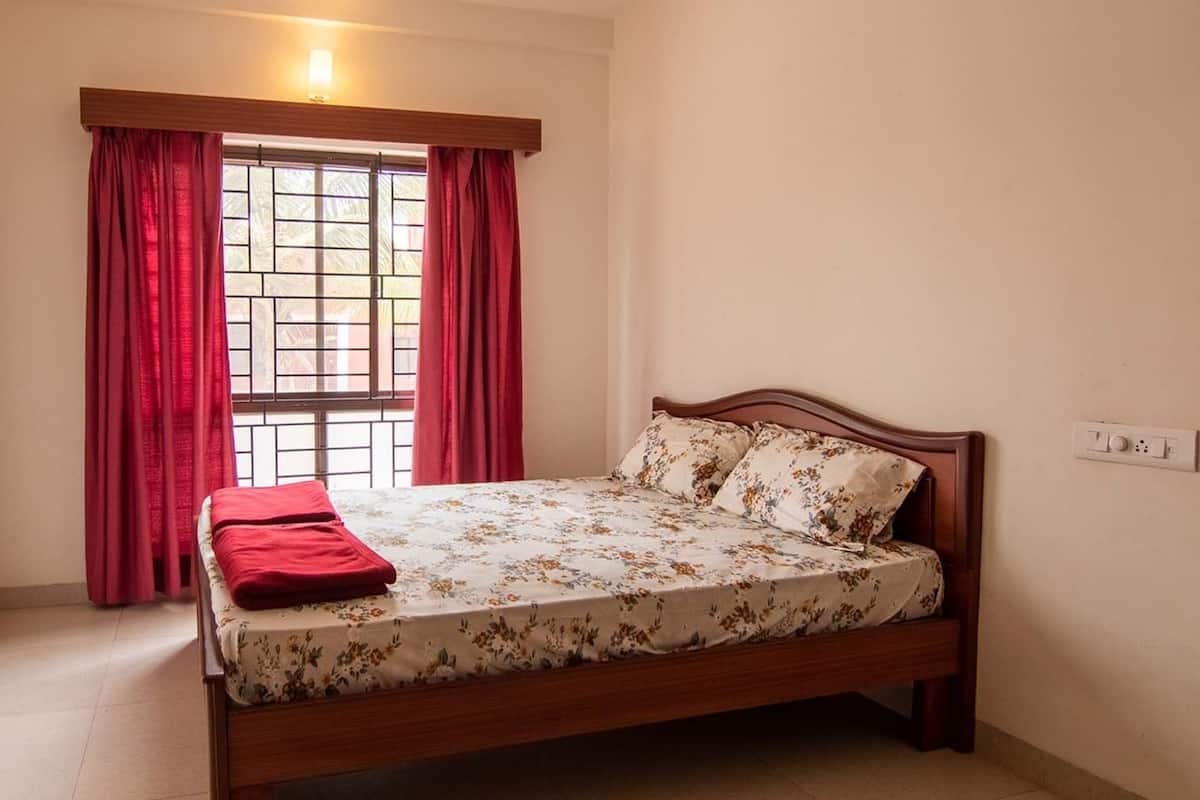 A bedroom with a wooden bed, red curtains, and a window with metal bars.