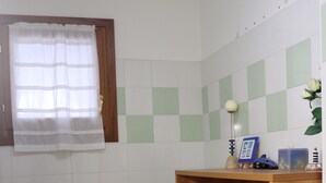 Ein Badezimmer mit Toilette, Waschbecken, Holzschrank und Fenster mit Vorhang.