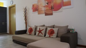 Ein Wohnzimmer mit einer Couch, einer Wanduhr und abstrakter Kunst.