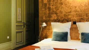 Habitación de hotel con una cama grande, una mesita de noche, una lámpara y una pared con textura.