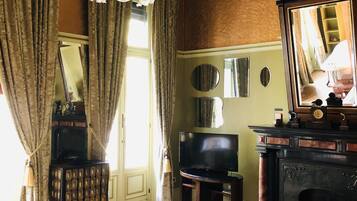 A room with a bed, a television, a fireplace, and a mirror on the wall.