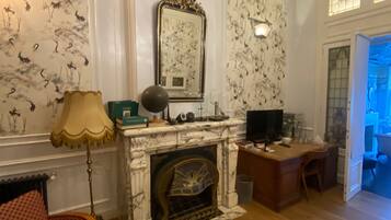 Une pièce avec une cheminée, un téléviseur, un bureau et un papier peint à motifs.