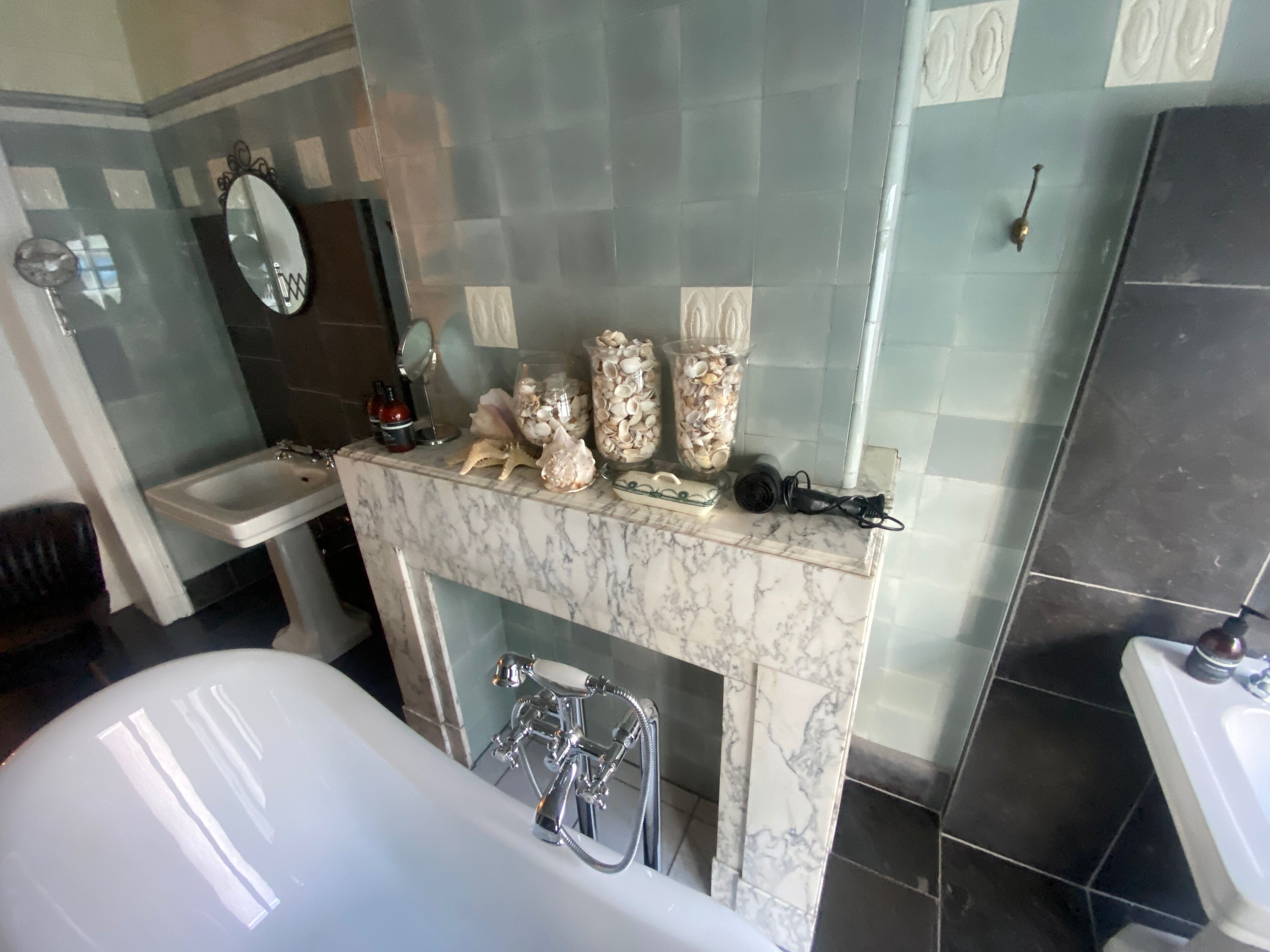 A bathroom with a marble vanity, a bathtub, and a sink.
