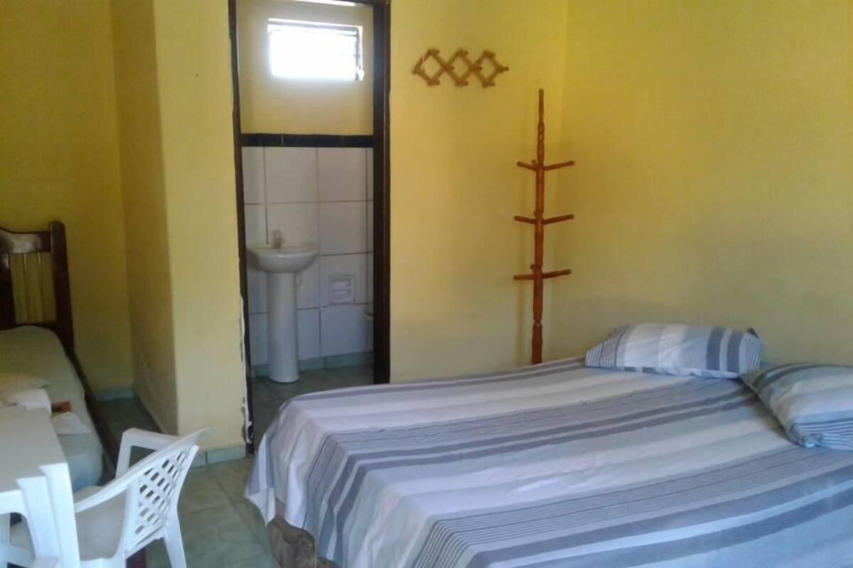 Ein Zimmer mit einem Bett, einem Schreibtisch und einem Stuhl. Ein Fenster und eine Tür führen ins Badezimmer.