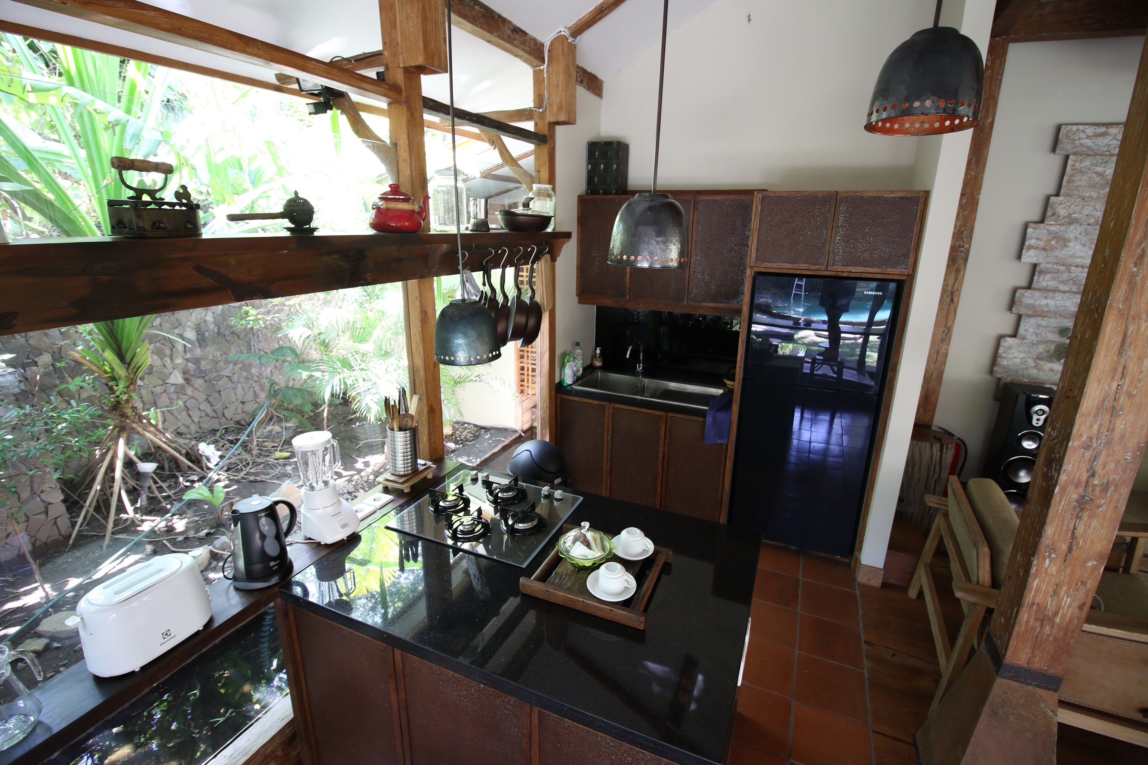 A kitchen with a black countertop, wooden cabinets, and a hanging pot rack.