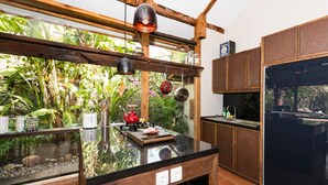 A kitchen with a black countertop, wooden cabinets, and a window overlooking a garden.