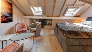 Un dormitorio acogedor en el ático con una cama estilo entrepiso, un televisor, un escritorio y una silla.